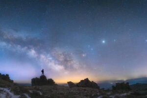 A man standing next to the Milky Way galaxy