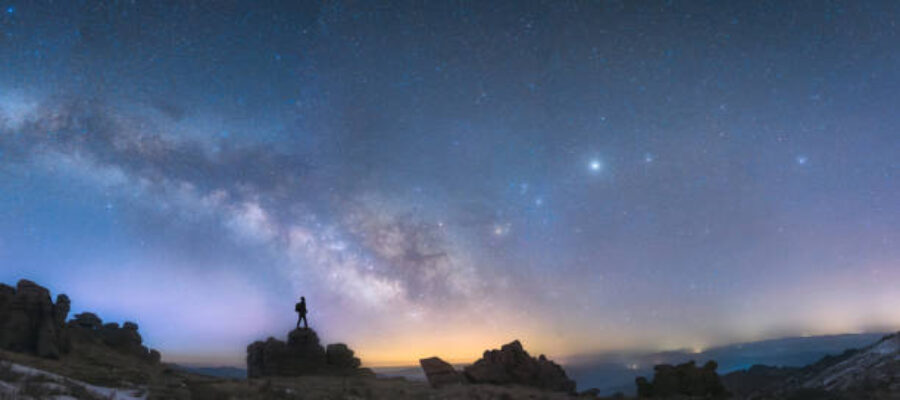 A man standing next to the Milky Way galaxy